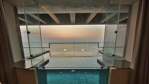 A glass-enclosed infinity pool with a view of the ocean at sunset. - Pledge Scape Negombo (Negombo)