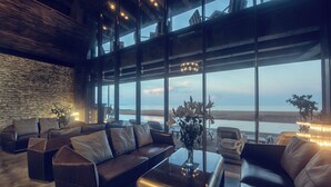 A spacious living area with a large window offering a view of the beach and ocean. - Pledge Scape Negombo (Negombo)