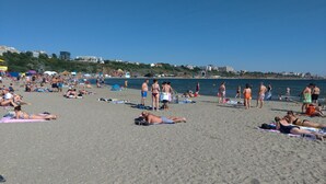 A crowded beach with people sunbathing and swimming.