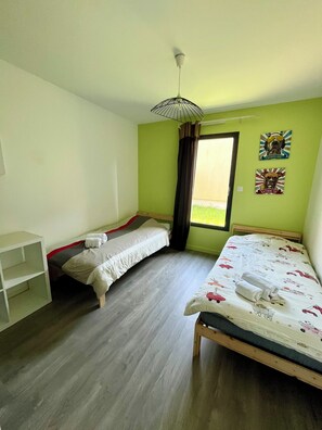 A room with two single beds, a desk, and a window with curtains.