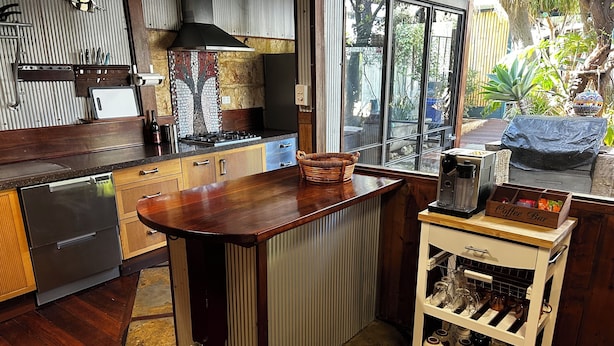 Een keuken met een houten eiland, een koffiehoek en uitzicht op de tuin.
