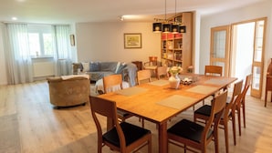 Un salón espacioso con una mesa de comedor de madera, sillas, un sofá y una estantería.