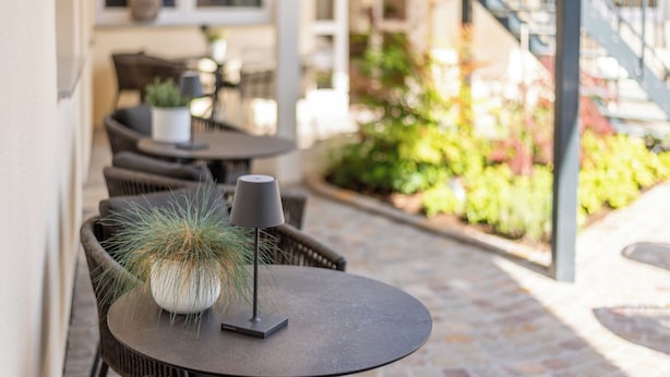 Un patio exterior con una mesa redonda, una planta en maceta y una silla.