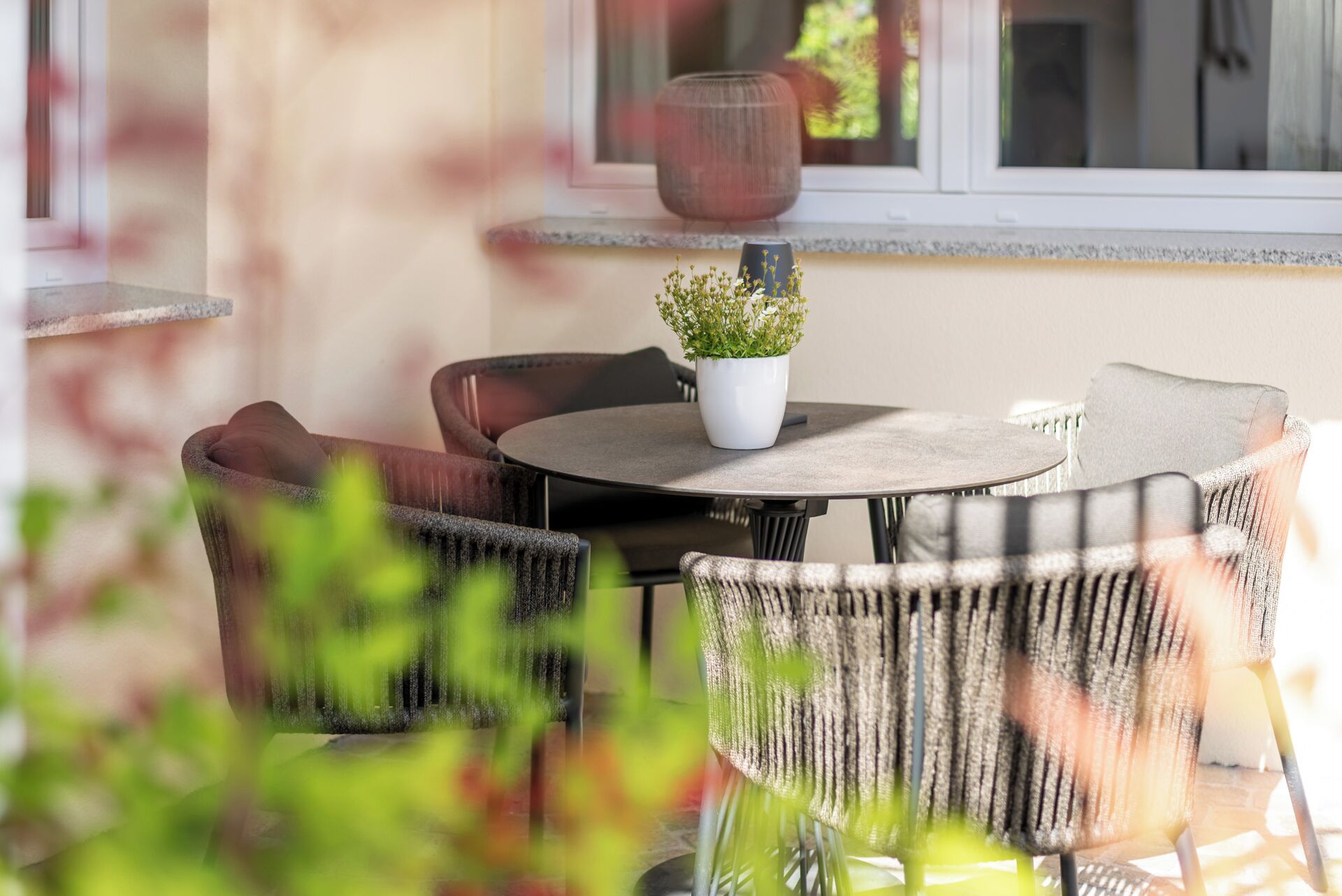 An outdoor seating area with a round table, chairs, and a potted plant.