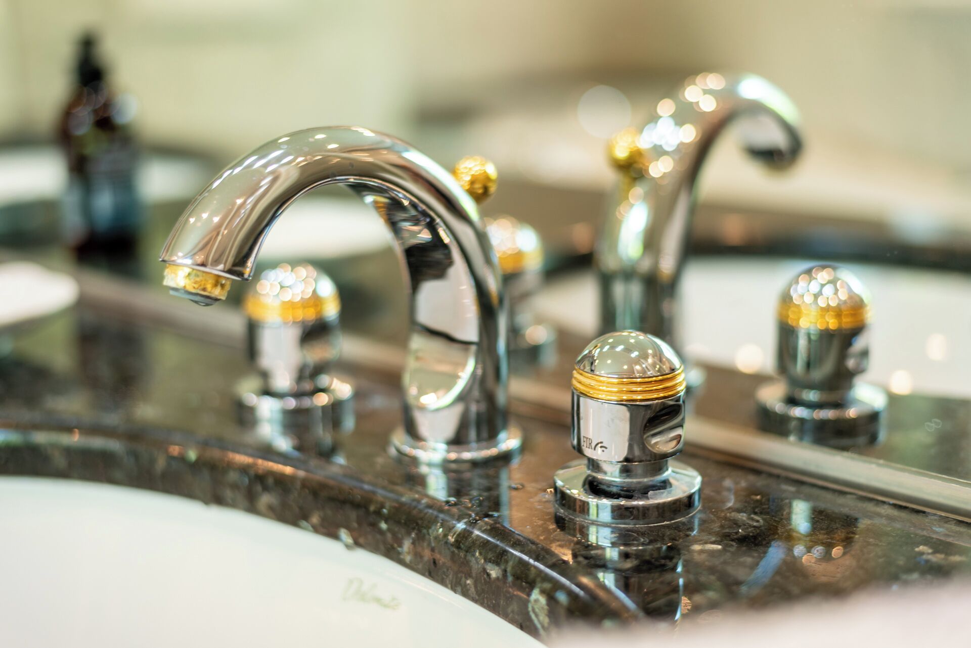 Ein Badezimmer mit modernem Wasserhahn und einem Spiegel, der den Bereich um das Waschbecken reflektiert.