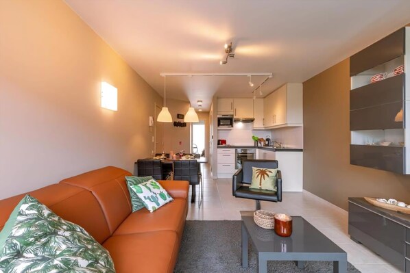 A modern apartment with a living room, dining area, and kitchen.