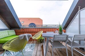 A balcony with a table, chairs, a sofa, and a chair.