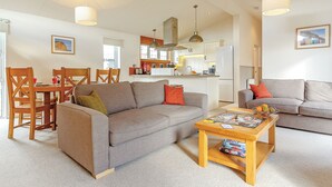 A living room with a sofa, a coffee table, and a dining area with chairs and a table.