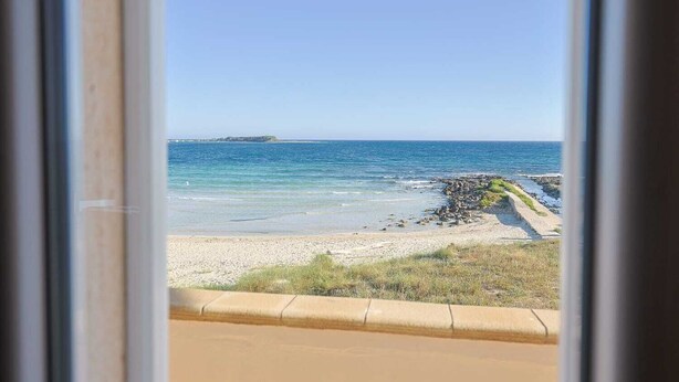 Vista de una playa con agua cristalina y una isla distante.