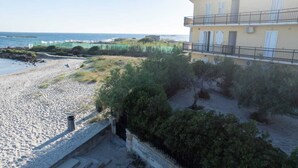 Una propiedad frente a la playa con vista al mar, un paseo pavimentado y un edificio con balcones.