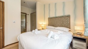 Une chambre d’hôtel avec un grand lit, une table de chevet avec une lampe et une armoire.