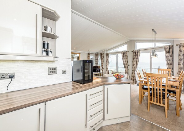 A modern kitchen with a refrigerator, stove, and dining area with chairs and a table.