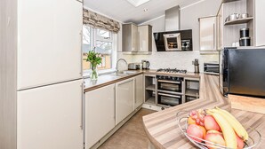 Une cuisine moderne avec des meubles blancs, une cuisinière à gaz, un four et un réfrigérateur.