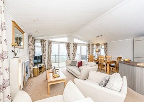 A modern living room with a sofa, coffee table, and dining area with chairs.