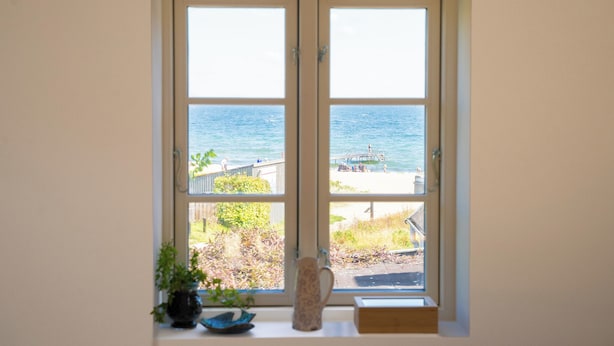 Ein Fenster mit Blick auf das Meer und einen Steg.