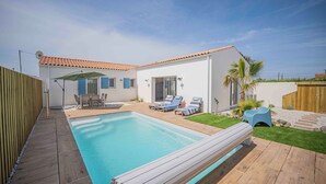 A backyard with a swimming pool, wooden deck, and outdoor seating area. - Villa Celestine - Ile d'Oléron - 6 pers - swimming pool (Saint-Denis-d'Oléron)
