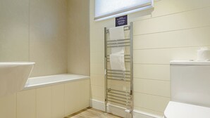 A bathroom with a toilet, a sink, a towel rack, and a window with blinds. - 1 bedroom accommodation in Axminster (Axminster)