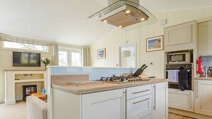 A modern kitchen with a central island, built-in oven, microwave, and a gas stove. - 1 bedroom accommodation in Axminster (Axminster)