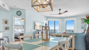 A spacious living area with a dining table, chairs, a ceiling fan, and a large window offering a view of the ocean. - Oceanfront Phoenix V Condo Gulf Views & Balcony  OrangeBeach 3Bed 2Bath 14th flr (Orange Beach)