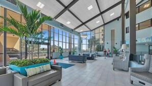 A spacious indoor area with seating arrangements, large windows, and potted plants. - Oceanfront Phoenix V Condo Gulf Views & Balcony  OrangeBeach 3Bed 2Bath 14th flr (Orange Beach)