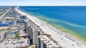 An aerial view of a coastal city with a long beachfront, high-rise buildings, and a parking lot. - Oceanfront Phoenix V Condo Gulf Views & Balcony  OrangeBeach 3Bed 2Bath 14th flr (Orange Beach)
