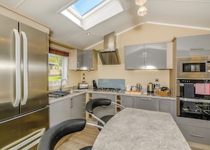 A modern kitchen with stainless steel appliances, a skylight, and a marble countertop.
