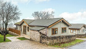 A two-story house with a stone foundation, a wooden deck, and a paved driveway. - 3 bedroom accommodation in Greystoke, Nr Ullswater (Greystoke, Nr Ullswater)