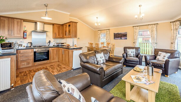 A compact living space with a kitchenette, leather sofas, a dining area, and a view of the outdoors. - 3 bedroom accommodation in Greystoke, Nr Ullswater (Greystoke, Nr Ullswater)