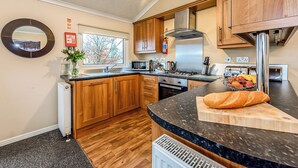 A modern kitchen with wooden cabinets, a stainless steel range hood, a microwave, and a large window. - 3 bedroom accommodation in Greystoke, Nr Ullswater (Greystoke, Nr Ullswater)