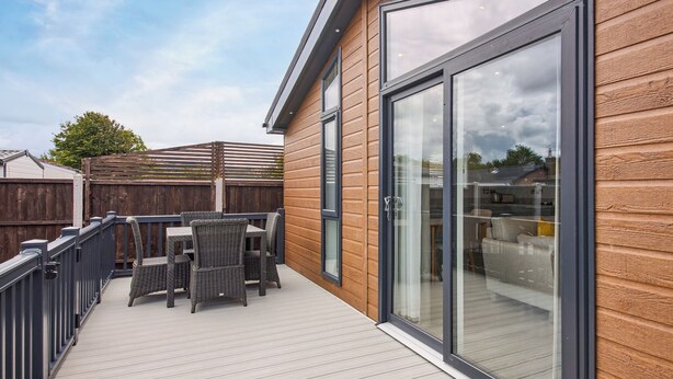 Terraza con mobiliario exterior, puerta corrediza de vidrio y pared exterior de madera.