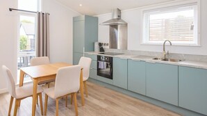 Una cocina moderna con armarios azul claro, una campana extractora de acero inoxidable, horno empotrado y una ventana con persianas.