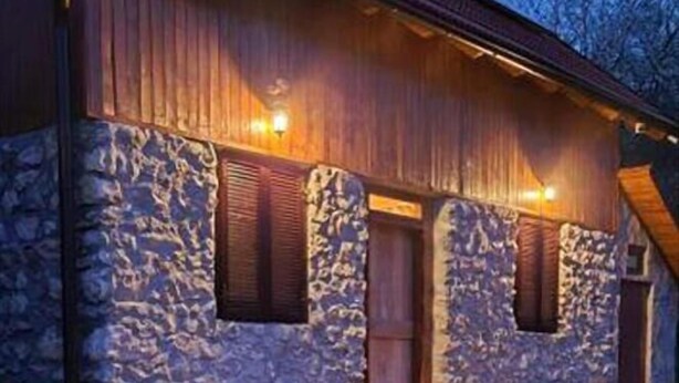 Un bâtiment en pierre doté d’un porche en bois et d’un escalier menant à une porte.