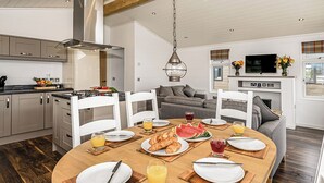 Une cuisine moderne avec un coin repas, un plancher en bois et une grande fenêtre.