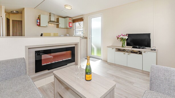 A modern living room with a fireplace, a television, and a dining area. - 2 bedroom accommodation in Talacre, Holywell (Talacre, Holywell)