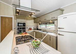 A modern kitchen with a gas stove, microwave, and a refrigerator. - 2 bedroom accommodation in Greystoke, Nr Ullswater (Greystoke, Nr Ullswater)