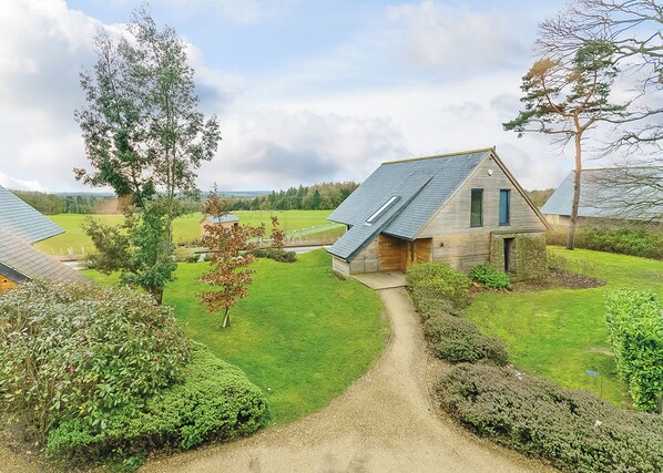 A modern house with a sloped roof, surrounded by well-maintained lawns and a gravel path.