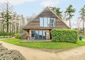 A modern house with a wooden exterior, large windows, and a well-maintained lawn.