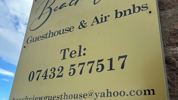 A sign for Beach View Guesthouse & Air bnbs with contact information.