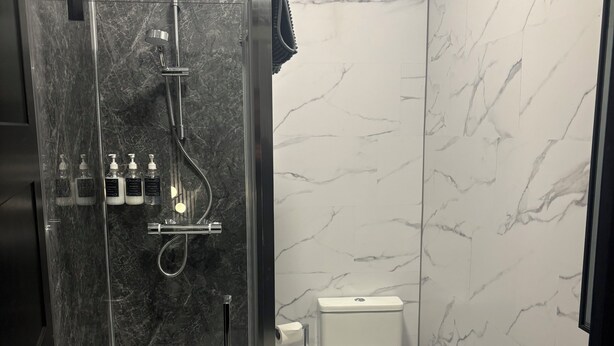 A modern bathroom with a glass-enclosed shower, a toilet, and a sink.