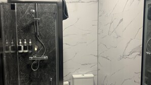 A modern bathroom with a glass-enclosed shower, a toilet, and a sink.