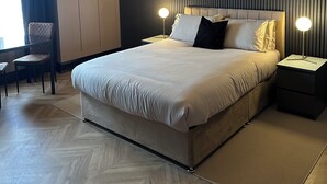 A modern hotel room with a large bed, two bedside tables with lamps, a chair, and a view of the outdoors. - Beachview  (Peterhead)