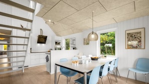 Eine moderne Küche mit weißen Schränken, einem eingebauten Herd und einem Essbereich mit einem großen Tisch und blauen Stühlen.