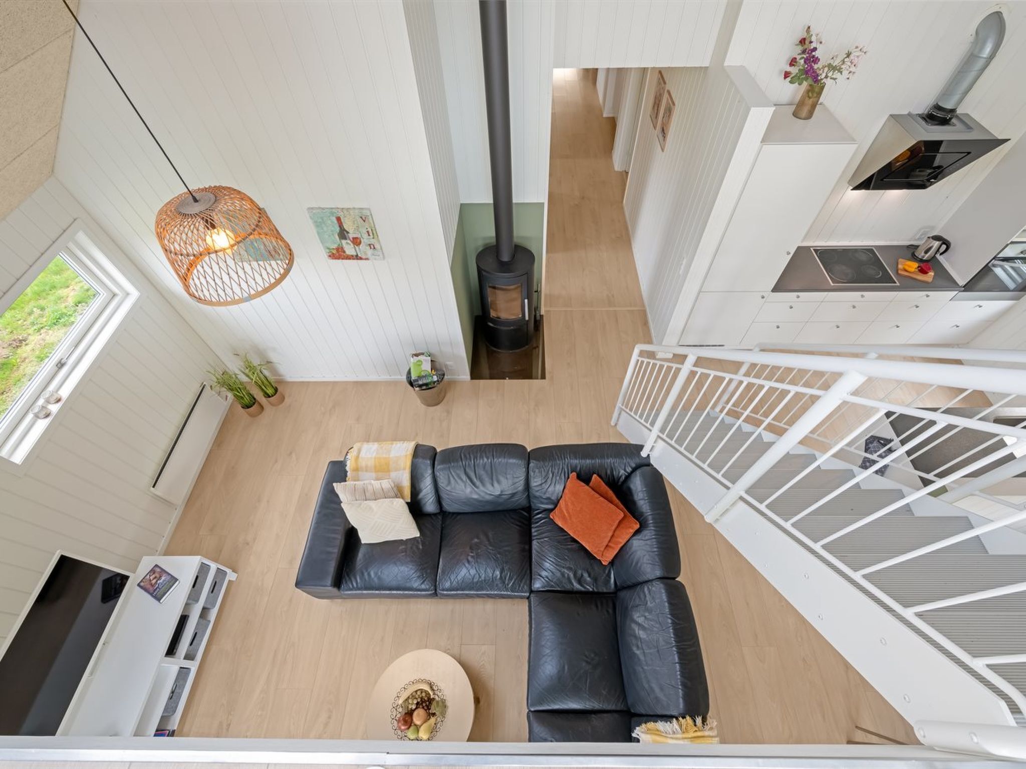 Een moderne woonkamer met een zwarte leren bank, een ronde salontafel en een hanglamp.