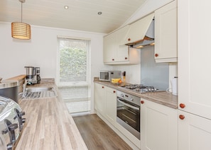 A modern kitchen with a wooden countertop, stainless steel appliances, and white cabinetry.