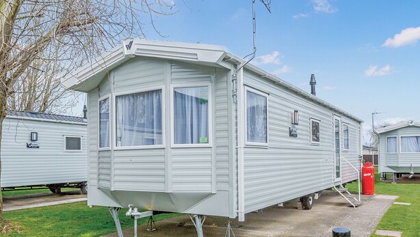 A mobile home with a front porch, windows, and a chimney. - 3 bedroom accommodation in Talacre, Holywell (Talacre, Holywell)