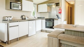 A compact kitchen with a microwave, toaster, kettle, stove, and a bench. - 3 bedroom accommodation in Talacre, Holywell (Talacre, Holywell)