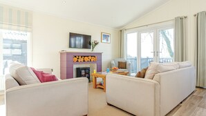 A living room with two sofas, a fireplace, a television, and a balcony. - 4 bedroom accommodation in Axminster (Axminster)