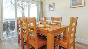 A dining area with a wooden table and chairs, a view through glass doors, and two framed pictures on the wall. - 4 bedroom accommodation in Axminster (Axminster)