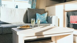 A modern living area with a sofa, a table with two glasses of champagne, and a plate of food. - 3 bedroom accommodation in Talacre, Holywell (Talacre, Holywell)