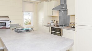 Una cocina moderna con horno empotrado, campana extractora de acero inoxidable y ventana que proporciona luz natural.